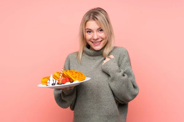 Jovem Loira Segurando Waffles Sobre Fundo Rosa Isolado Com Expressão — Fotografia de Stock