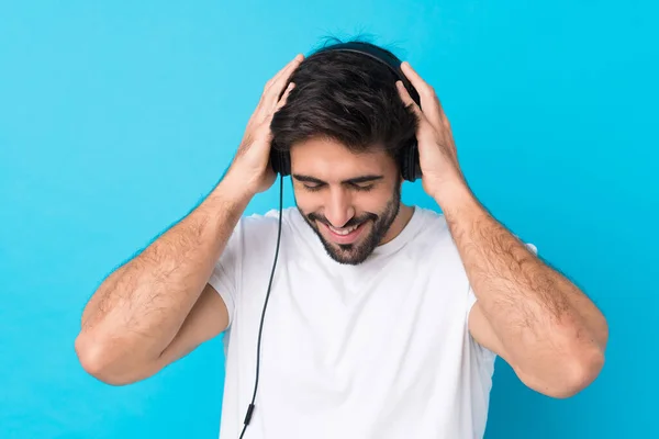 Νέος Όμορφος Άντρας Γενειάδα Πάνω Από Απομονωμένο Μπλε Φόντο Ακούγοντας — Φωτογραφία Αρχείου