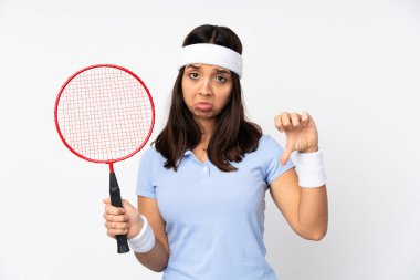 İzole edilmiş beyaz arka planda genç badmintoncu kadın baş parmağını aşağı gösteriyor.