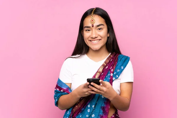 Young Indian woman with sari over isolated background sending a message with the mobile