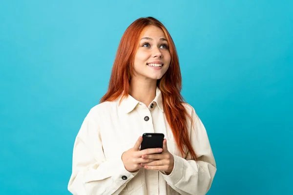 Έφηβη Ρωσίδα Απομονωμένη Μπλε Φόντο Χρησιμοποιώντας Κινητό Τηλέφωνο Και Κοιτώντας — Φωτογραφία Αρχείου