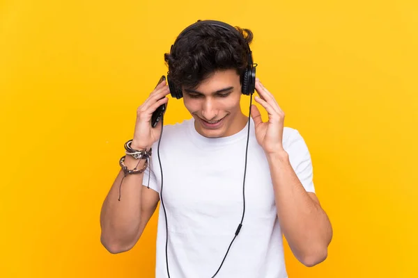 Νεαρός Αργεντίνος Ακούει Μουσική Ένα Κινητό Πάνω Από Απομονωμένο Κίτρινο — Φωτογραφία Αρχείου