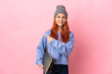 Pembe arka planda izole edilmiş genç bir Rus kız. Paten kayıyor ve yan tarafı işaret ediyor.