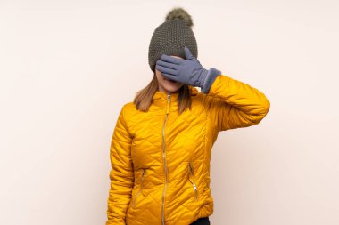 Kış şapkalı kadın izole arka planda gözlerini elleriyle kapatıyor.