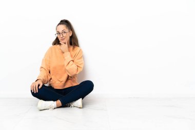 Genç bir kadın yerde oturmuş, yukarı bakarken bir fikir düşünüyor.