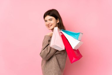 Genç Ukraynalı izole pembe arka planda genç bir kız alışveriş torbaları tutuyor ve gülümsüyor.