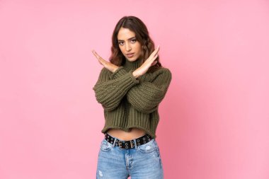 Soyutlanmış pembe arka planı olan genç bir kadın jest yapmıyor.
