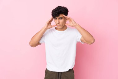 Arjantinli genç bir adam soyutlanmış pembe arka planda mutsuz ve hayal kırıklığına uğramış. Olumsuz yüz ifadesi