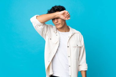 Arjantinli genç adam arka planda izole edilmiş, gözleri elle kapatılmış.