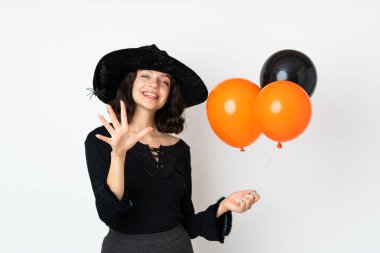 Siyah ve turuncu hava balonları tutan genç cadı parmaklarıyla beşi sayıyor.