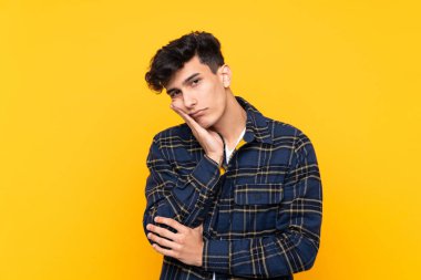 Arjantinli genç adam izole edilmiş sarı arka planda mutsuz ve hayal kırıklığına uğramış