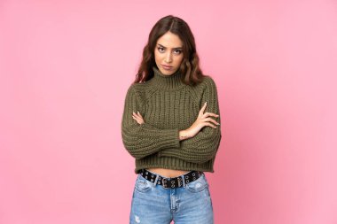 Soyutlanmış pembe arka planı olan genç bir kadın üzgün.