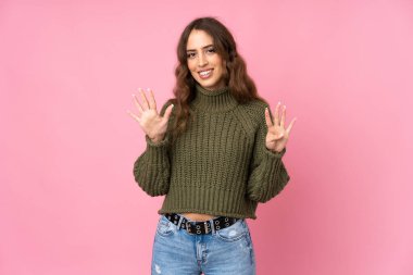 Soyutlanmış pembe arka planda dokuz parmaklı genç kadın.