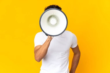 Arjantinli genç adam sarı arka planda izole edilmiş megafonla bir şey duyurmak için bağırıyor.