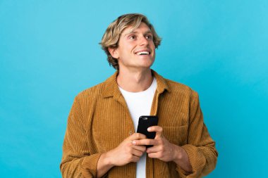 İngiliz adam cep telefonu kullanarak mavi arka planda izole edilmiş.