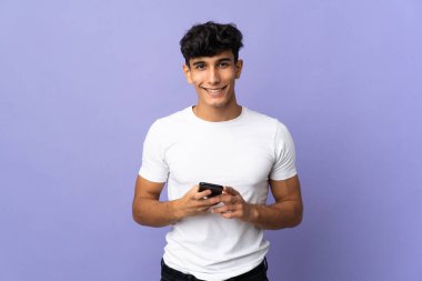 Arjantinli genç adam arka planda izole edilmiş cep telefonuyla mesaj gönderiyor.