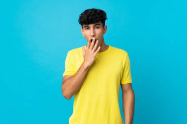 Arjantinli genç adam arka planda izole edilmiş esniyor ve ağzını eliyle açık tutuyor.