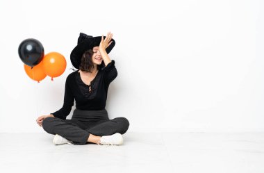 Yerde duran siyah ve turuncu balonları tutan genç cadı bir şeyin farkına vardı ve çözümü amaçladı.