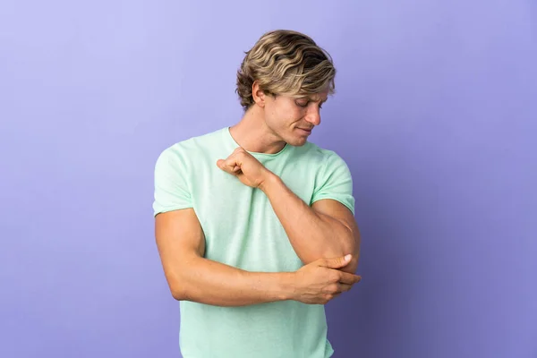 English man over isolated purple background with pain in elbow