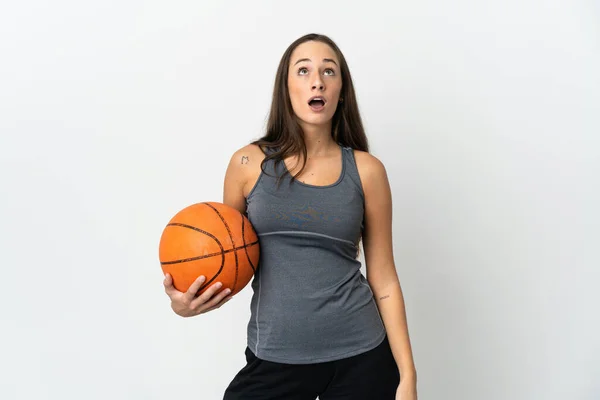 若いです女性プレイバスケットボール上の隔離された白い背景見上げととともに驚きの表情 — ストック写真