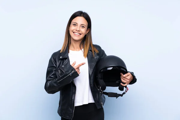 若いですブルネット女性保持Aオートバイヘルメット以上隔離された青の背景とそれを指す — ストック写真