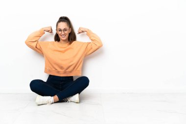 Yerde oturan genç bayan güçlü bir jest yapıyor.