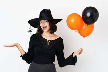 Siyah ve turuncu hava balonları tutan genç cadı şok olmuş yüz ifadesi ile