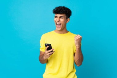 Arjantinli genç adam arka planda izole edilmiş ve telefon zafer pozisyonunda.