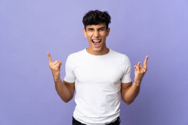 Arjantinli genç adam arka planda izole edilmiş boynuz hareketi yapıyor.