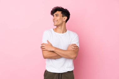 Arjantinli genç adam soyutlanmış pembe arka planda gülüyor