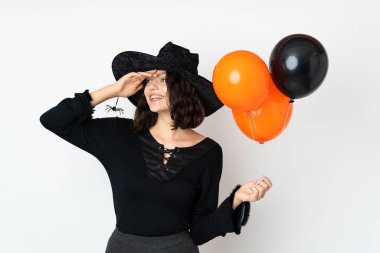 Siyah ve turuncu hava balonları tutan genç cadı çok gülümsüyor.