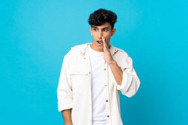 Arjantinli genç adam arka planda izole edilmiş. Yan tarafa bakarken sürpriz bir jest yapıyor.