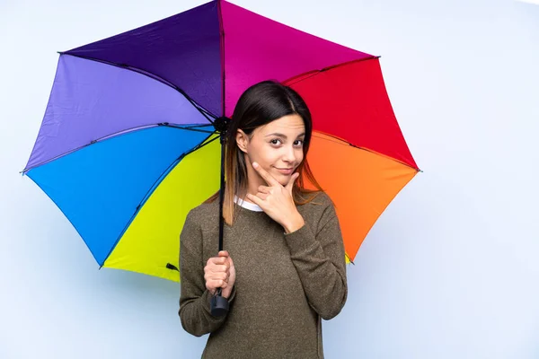 Joven Morena Sosteniendo Paraguas Sobre Una Pared Azul Aislada Pensando — Foto de Stock