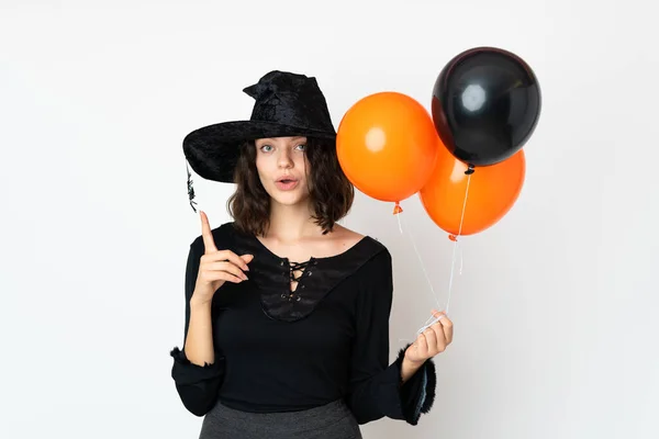 指を持ち上げながら溶液を実現しようとする黒とオレンジの空気気球を保持若い魔女 — ストック写真