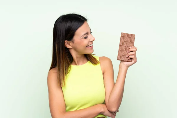 Žena Izolovaném Zeleném Pozadí Čokoládovou Tabletu Šťastný — Stock fotografie