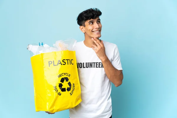Young Argentinian man holding a bag full of plastic looking up while smiling