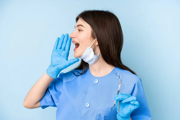 Junge Zahnärztin Hält Werkzeug Über Isolierten Blauen Hintergrund Und Schreit — Stockfoto