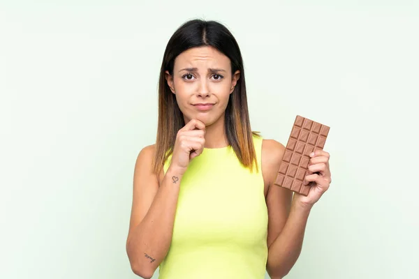 Žena Izolovaném Zeleném Pozadí Čokoládovou Tabletu Mají Pochybnosti — Stock fotografie