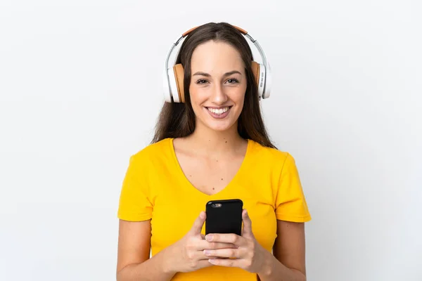 Молода Іспаномовна Жінка Над Ізольованим Білим Тлом Слухає Музику Мобільним — стокове фото
