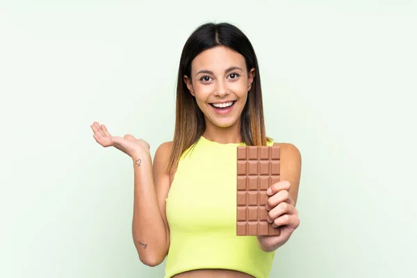 Žena Nad Izolovaným Zeleným Pozadím Tabletou Čokolády Překvapen — Stock fotografie