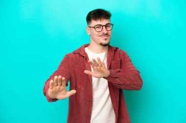 Beyaz tenli yakışıklı adam mavi arka planda izole edilmiş gergin eller öne uzanıyor.
