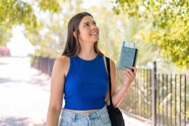 Genç, güzel Brezilyalı bir kadın, elinde pasaport, dışarı bakıyor ve gülümsüyor.