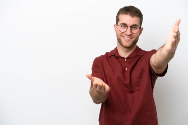 Beyaz arka planda izole edilmiş genç beyaz bir adam sunar ve davet eder.