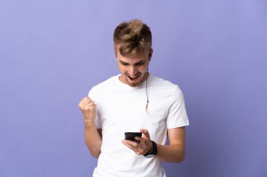 Mor arka planda izole genç yakışıklı sarışın adam şaşırdı ve bir mesaj gönderiyor.