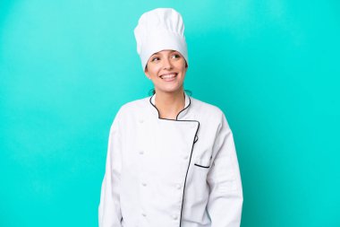 Kafkasyalı genç aşçı kadın mavi arka planda izole edilmiş gülüyor.