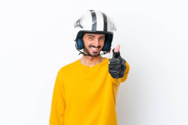 Motosiklet kasklı beyaz tenli genç adam beyaz arka planda izole edildi. Başparmakları havada çünkü iyi bir şey oldu.