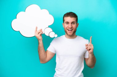 Young caucasian man isolated on blue background holding a thinking speech bubble