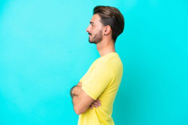 Kafkasyalı genç adam mavi arka planda yan pozisyonda izole edildi.