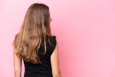 Genç beyaz kadın pembe arka planda izole edilmiş arka planda ve yan bakıyor.