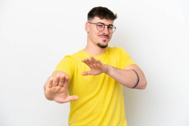 Beyaz arka planda soyutlanmış beyaz tenli yakışıklı adam ellerini öne uzatıyor.